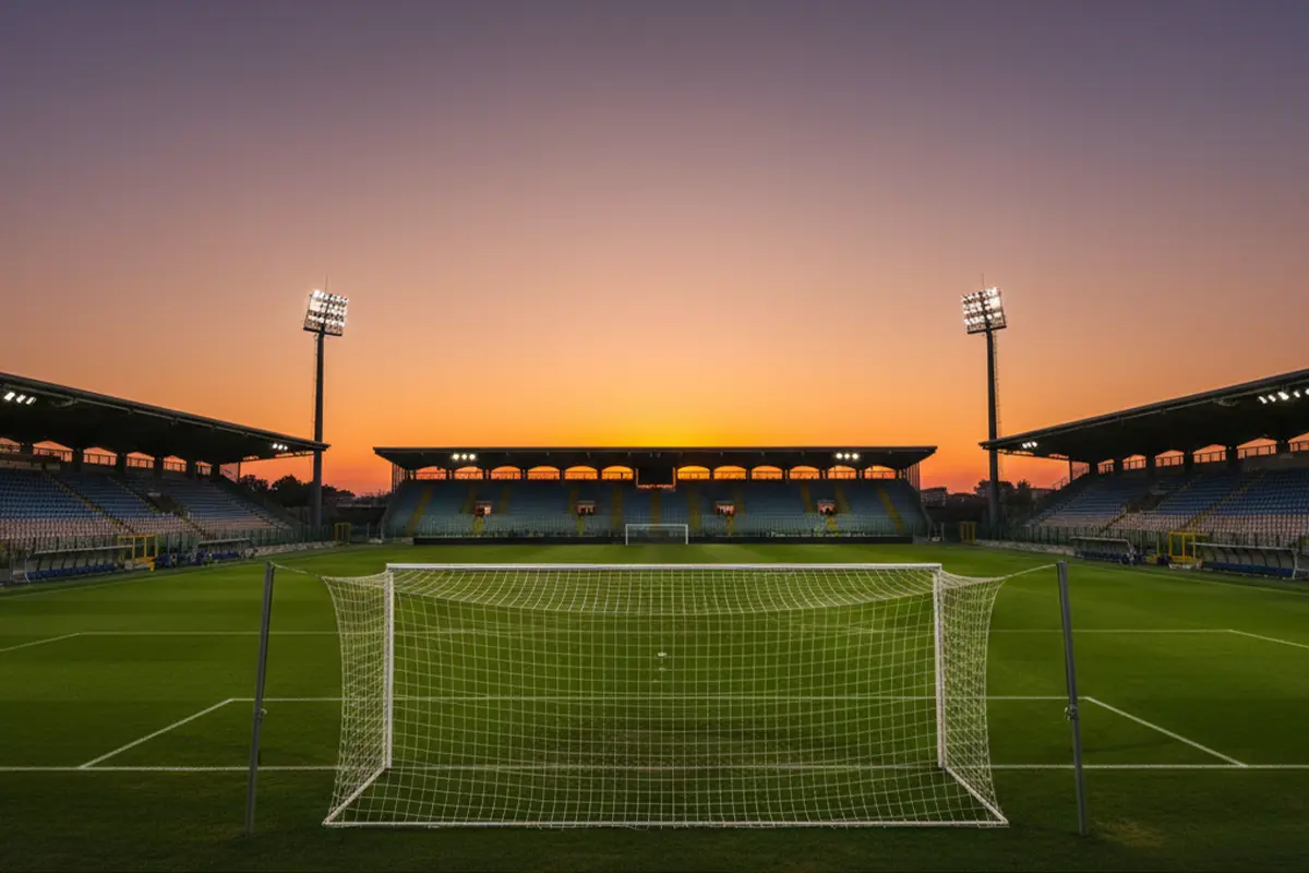 Panoramica di uno stadio di calcio italiano al tramonto con il campo da gioco illuminato