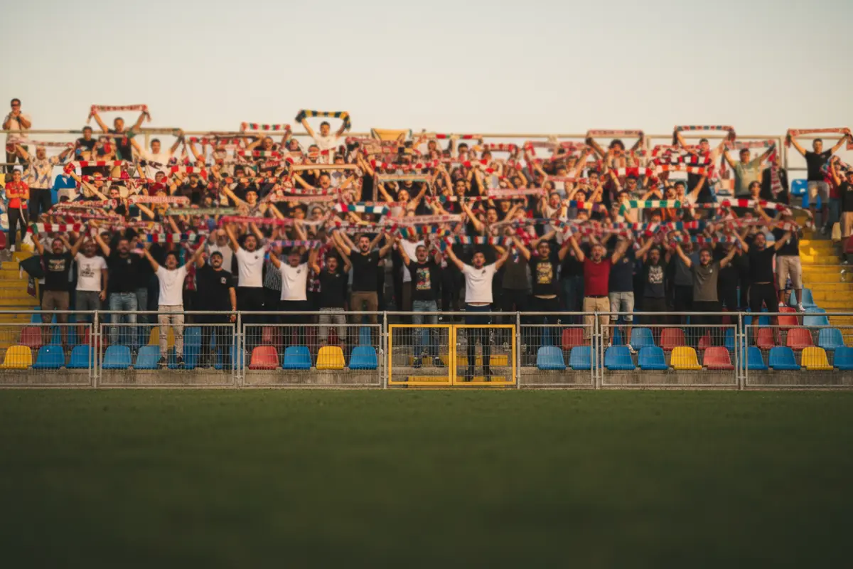 Tifosi di una squadra outsider di Serie A esultano sugli spalti di uno stadio italiano dopo una vittoria inaspettata